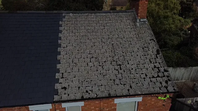 A roof has dark slates on one side and weathered uneven slates on the other.