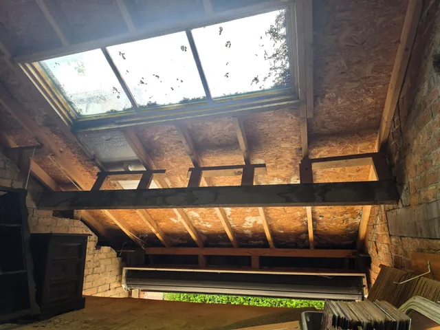 Garage roof timbers and dark beams surround a glazed rooflight viewed from below.