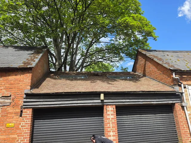 An old garage roof sits between brick gables above two dark roller doors.