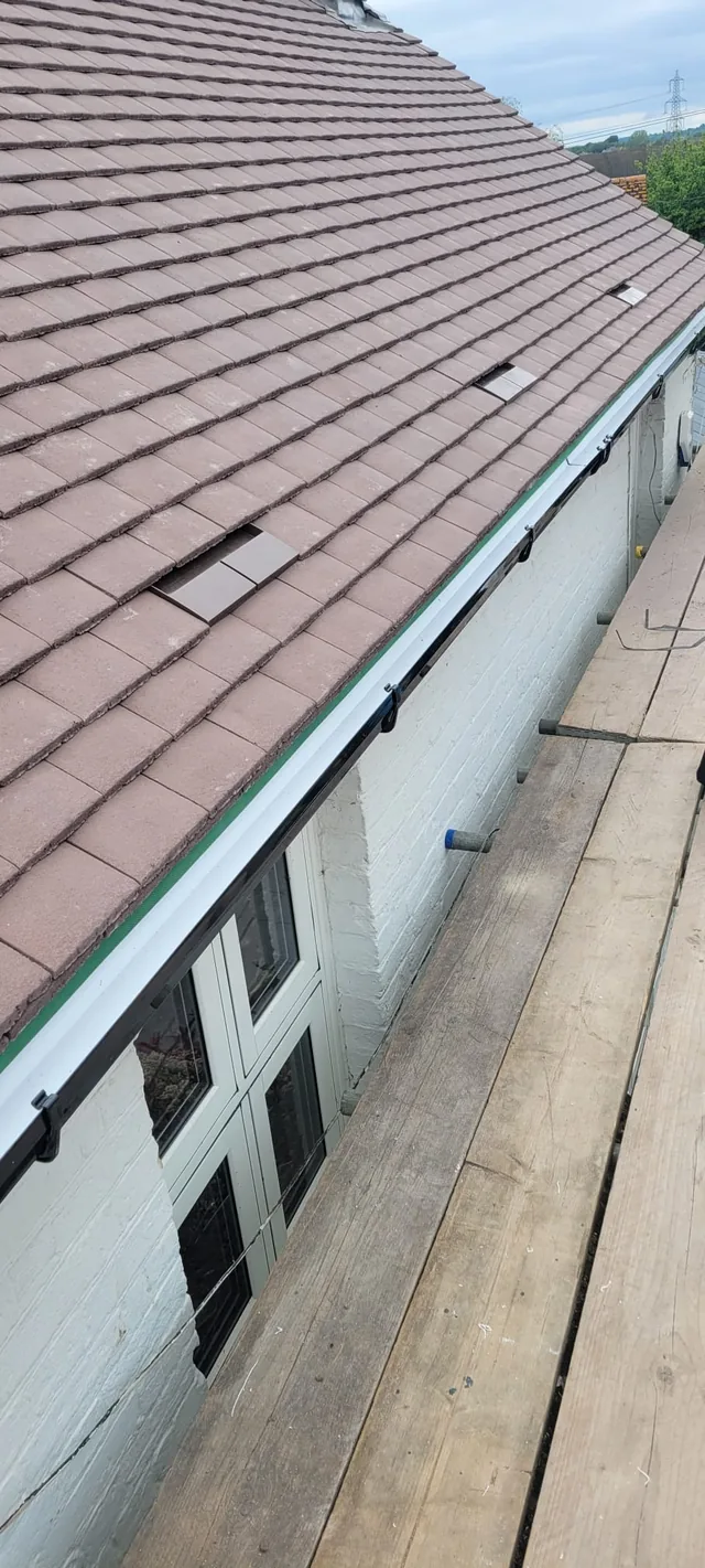 White fascia and dark brackets run beneath brown roof tiles with rectangular vents.