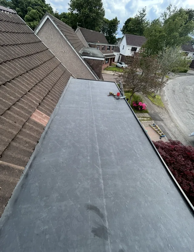 Grey sheet roofing bears chalk lines and footprints beside tiles, tools and a garden.