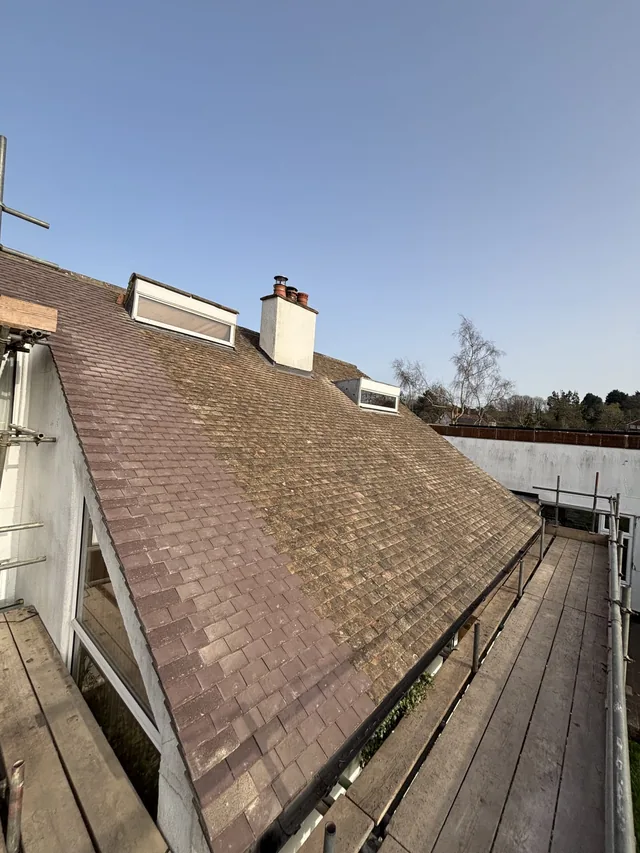 Reused brown tiles cover a broad roof slope around rooflights and a white chimney.