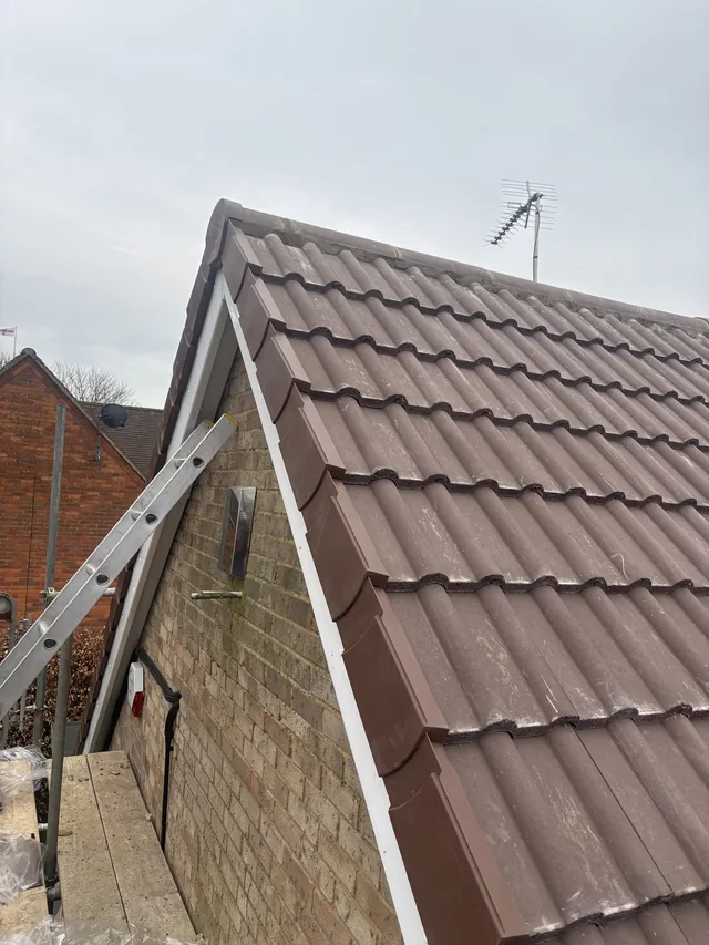 Brown interlocking tiles cover a gabled roof with matching verge caps and white trim.